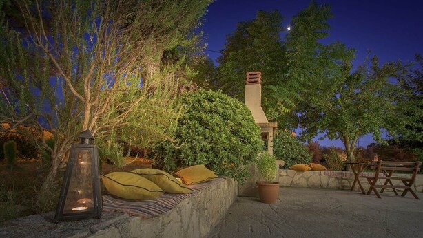 An outdoor seating area with a stone wall, cushions, a lantern, and a potted plant. - Alba Boutique Apartments (Zakynthos)