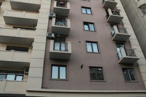 A multi-story residential building with balconies, air conditioning units, and windows.