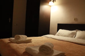A hotel room with a neatly made bed, a bedside lamp, and a wall-mounted light fixture.