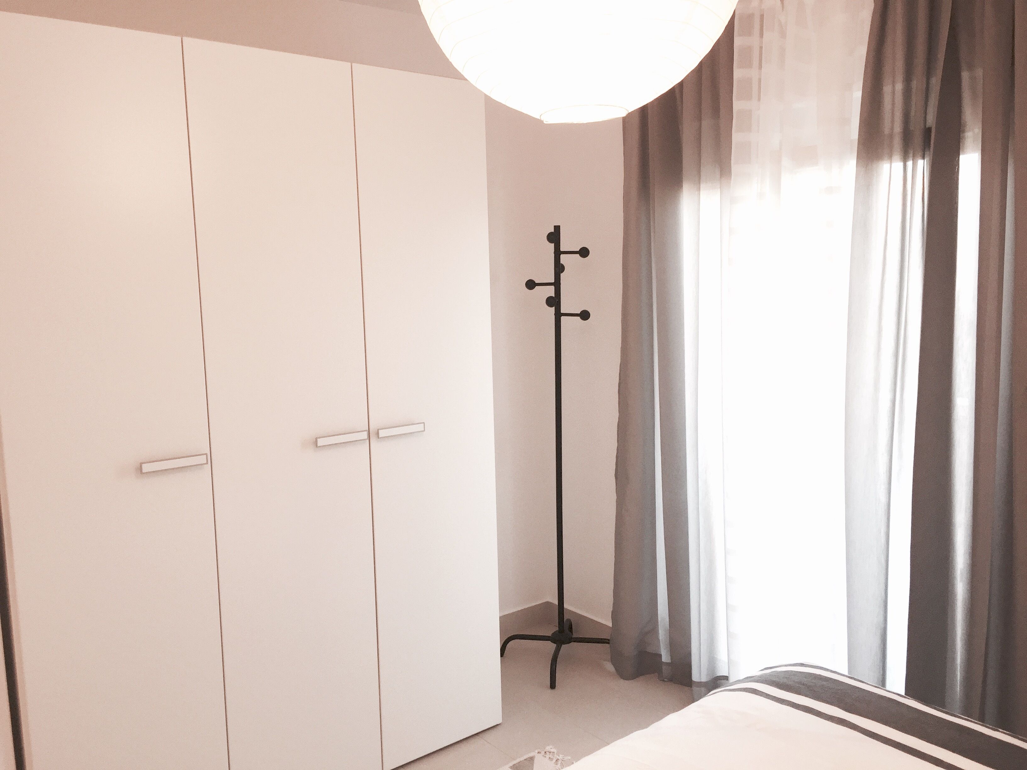 Een slaapkamer met een grote kast, een kapstok en een bed.