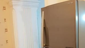 A kitchen with a refrigerator, a white column, and patterned wallpaper. - Apartament on Shartava str. (Tbilisi)