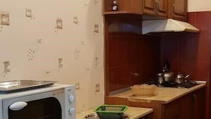 A kitchen with a microwave, stove, and wooden cabinets. - Apartament on Shartava str. (Tbilisi)