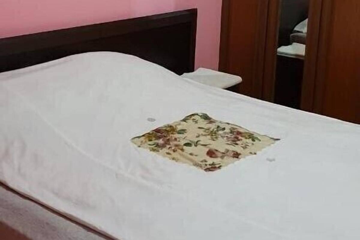 Un dormitorio con una cama individual, un armario de madera y un cuadro en la pared.