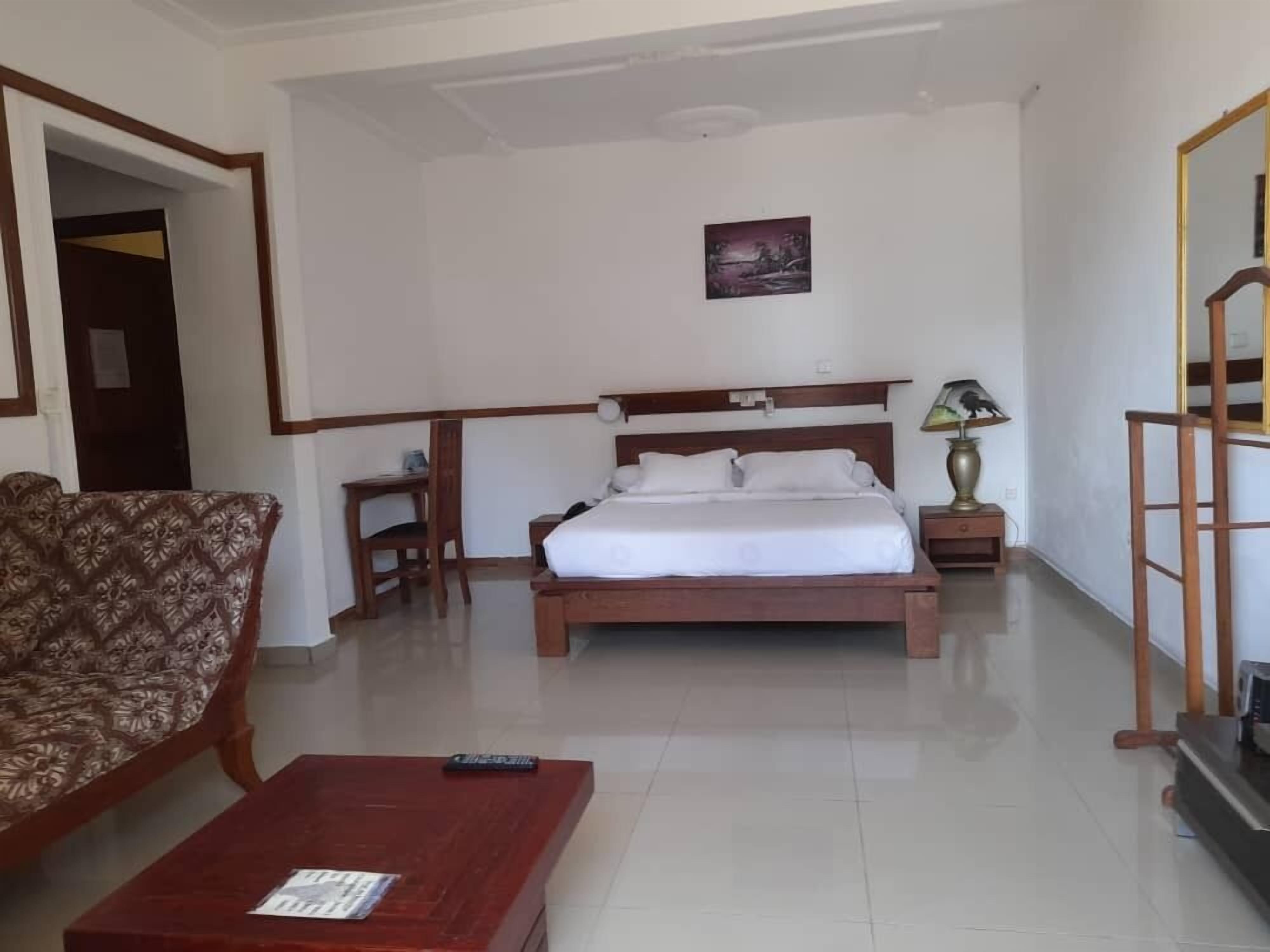 Una habitación de hotel con cama, escritorio, silla, mesita de centro y lámpara.