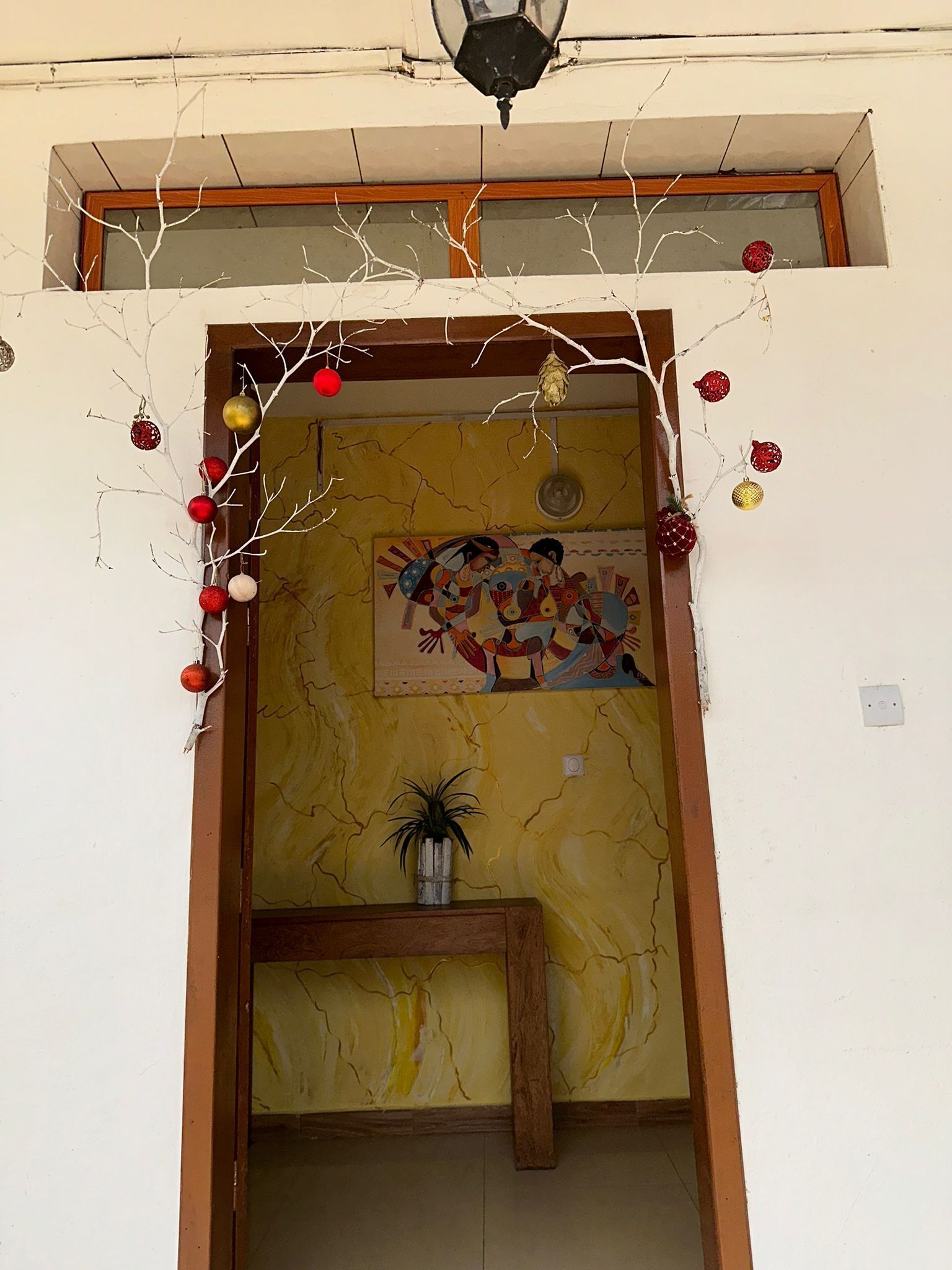 Un vano con arco decorativo, un cuadro y una pequeña mesa con una planta.