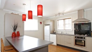 Una cocina moderna con una isla central, electrodomésticos de acero inoxidable e iluminación colgante.