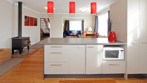 Una cocina moderna con armarios blancos, una isla central, un microondas y lámparas colgantes rojas.