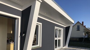 A modern house with a dark exterior, white trim, and a tiled patio. - Pension Zur Kirchsee (Insel Poel)