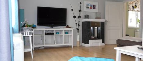 Una sala de estar moderna con televisor de pantalla plana, muebles blancos, chimenea y vistas al exterior.