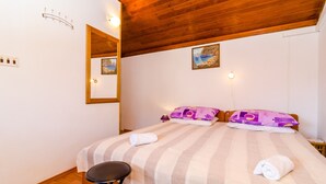Ein Schlafzimmer mit Holzbalkendecke, einem Bett mit gestreifter Bettwäsche, zwei Kissen, einem Spiegel und einem kleinen Tisch.