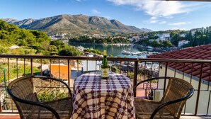 Ein Balkon mit einem Tisch für zwei Personen, mit Blick auf einen See, auf dem Boote fahren, und eine Stadt im Hintergrund.