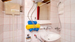 Ein Badezimmer mit Toilette, Waschbecken, Dusche und Handtuchhalter.