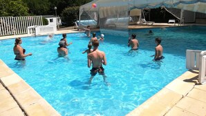 Una piscina con una zona cubierta y una cerca blanca al fondo.