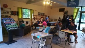 Un comedor con mesas y sillas, una exhibición de libros y un cartel que anuncia una propiedad.