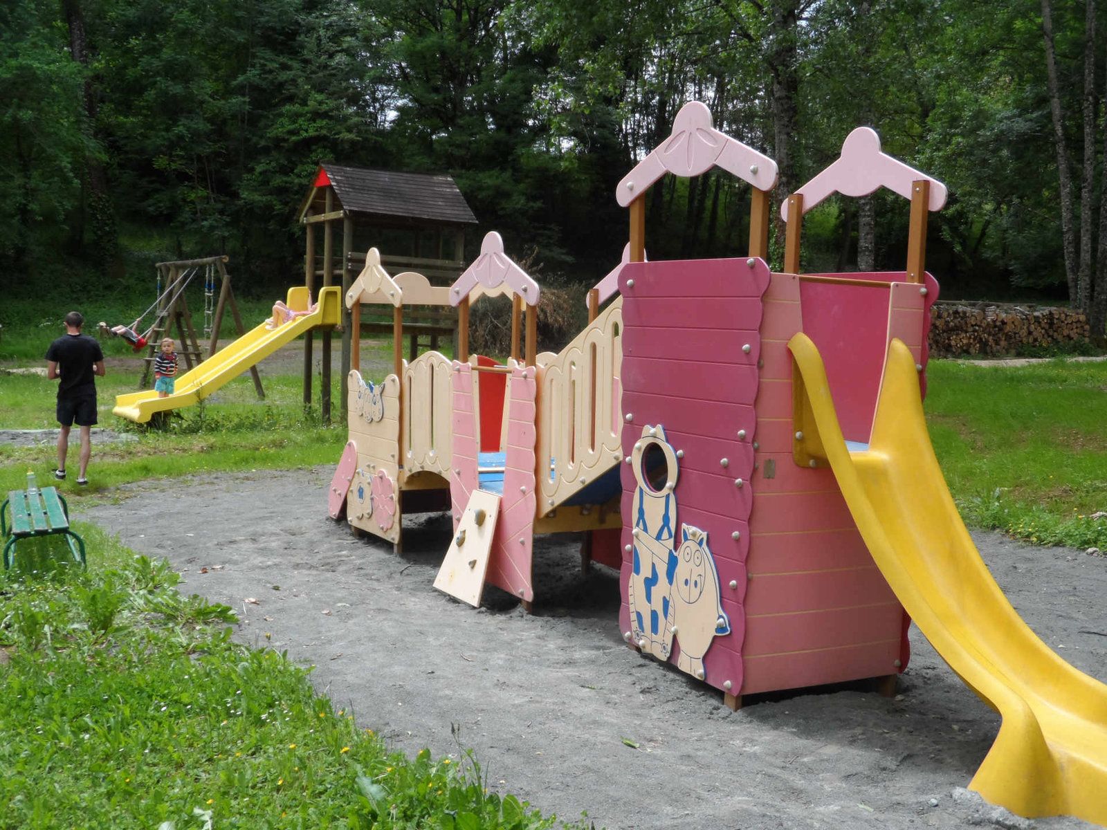 A playground with a slide, climbing structures, and a small building.
