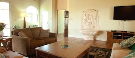 A living room with a sofa, a coffee table, a television, and a decorative fountain.