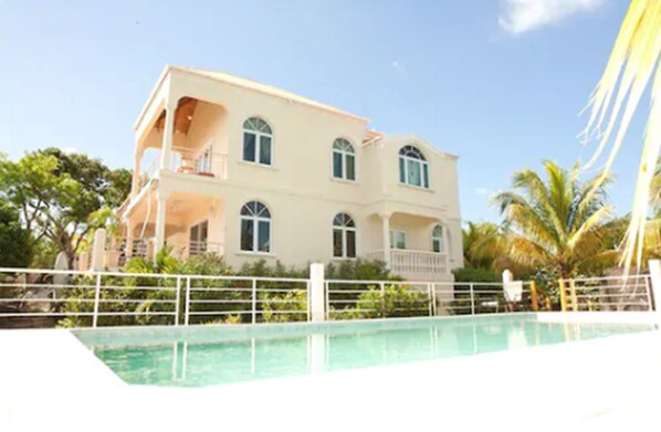A two-story building with a balcony and a swimming pool in front. - Coconut Tree Villa (East End)
