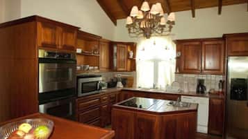 Cocina con armarios de madera, electrodomésticos de acero inoxidable y una isla central.