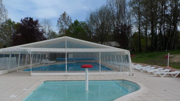A covered swimming pool with lounge chairs and a canopy.