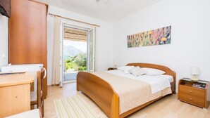 Une chambre à coucher avec un lit, un bureau et une chaise. Il y a une fenêtre qui donne sur un paysage verdoyant.