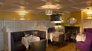 A dining area with a fireplace, tables set for dining, and a television mounted on the wall.