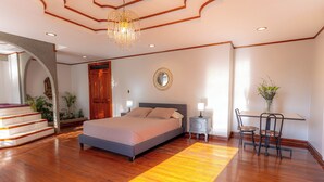 A bedroom with a bed, a desk, a chair, a mirror, and a staircase. - Casa Familiar la Tortuga (San Pablo)