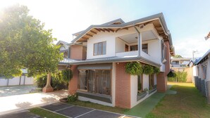 A two-story house with a balcony, large windows, and a small front yard. - Casa Familiar la Tortuga (San Pablo)
