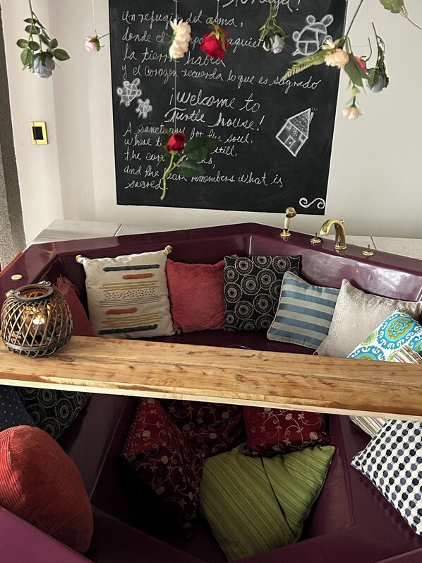A cozy seating area with a cushioned bench, a wooden shelf, and a variety of pillows.