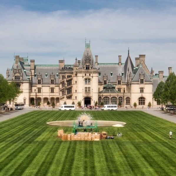 A large, historic building with a symmetrical facade, a central entrance, and a well-maintained lawn in front.