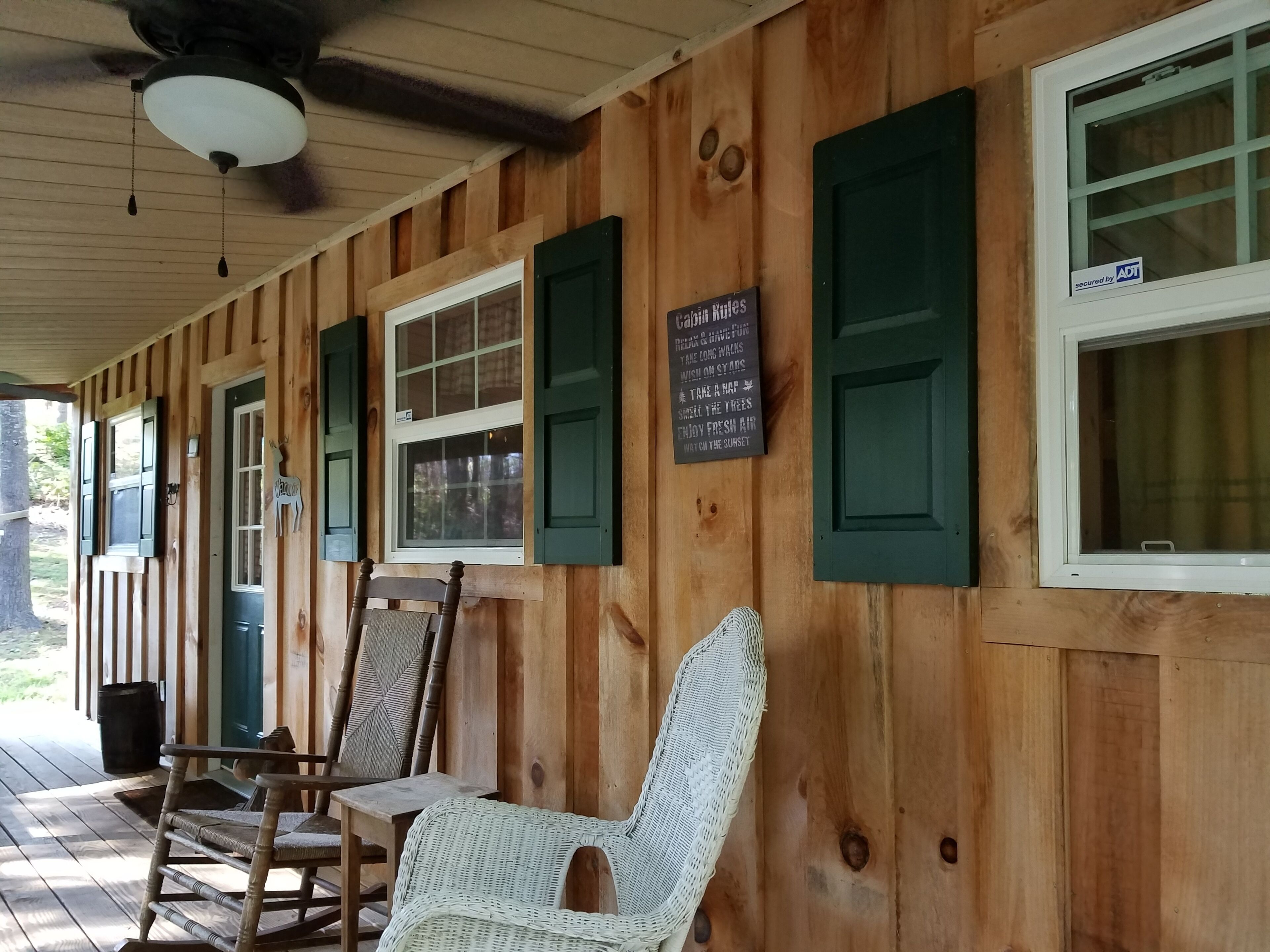 Eine Holzhütte mit Veranda, grünen Fensterläden und einem Schild.
