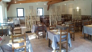 Un comedor con vigas de madera, mesas con manteles azules y sillas.