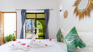 A hotel room with a bed, a window with curtains, a view of the outside, and a wall-mounted mirror. - Marea Boutique Hotel (Jambiani)