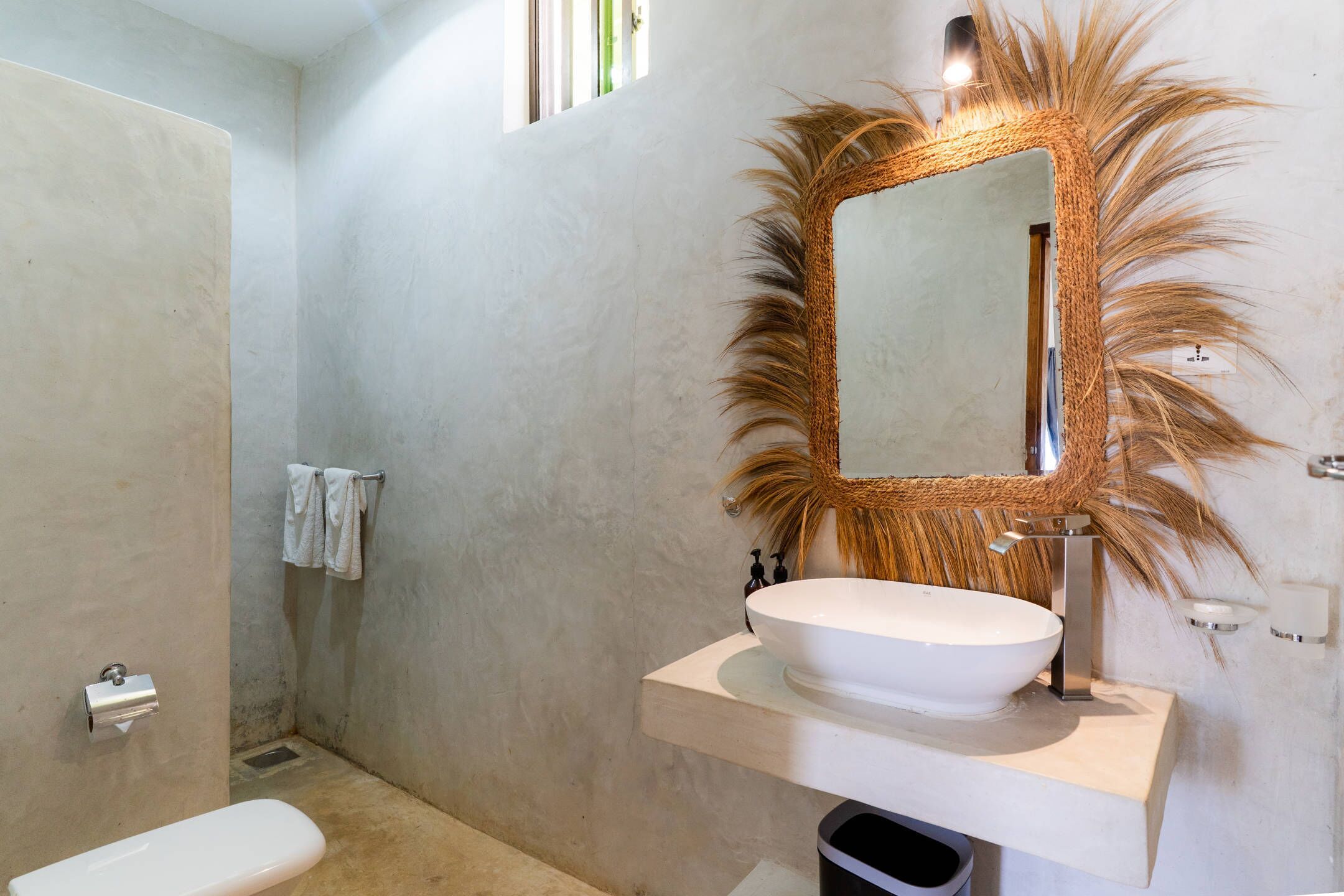 A bathroom with a white sink, a large mirror with a textured frame, and a towel rack with two towels.