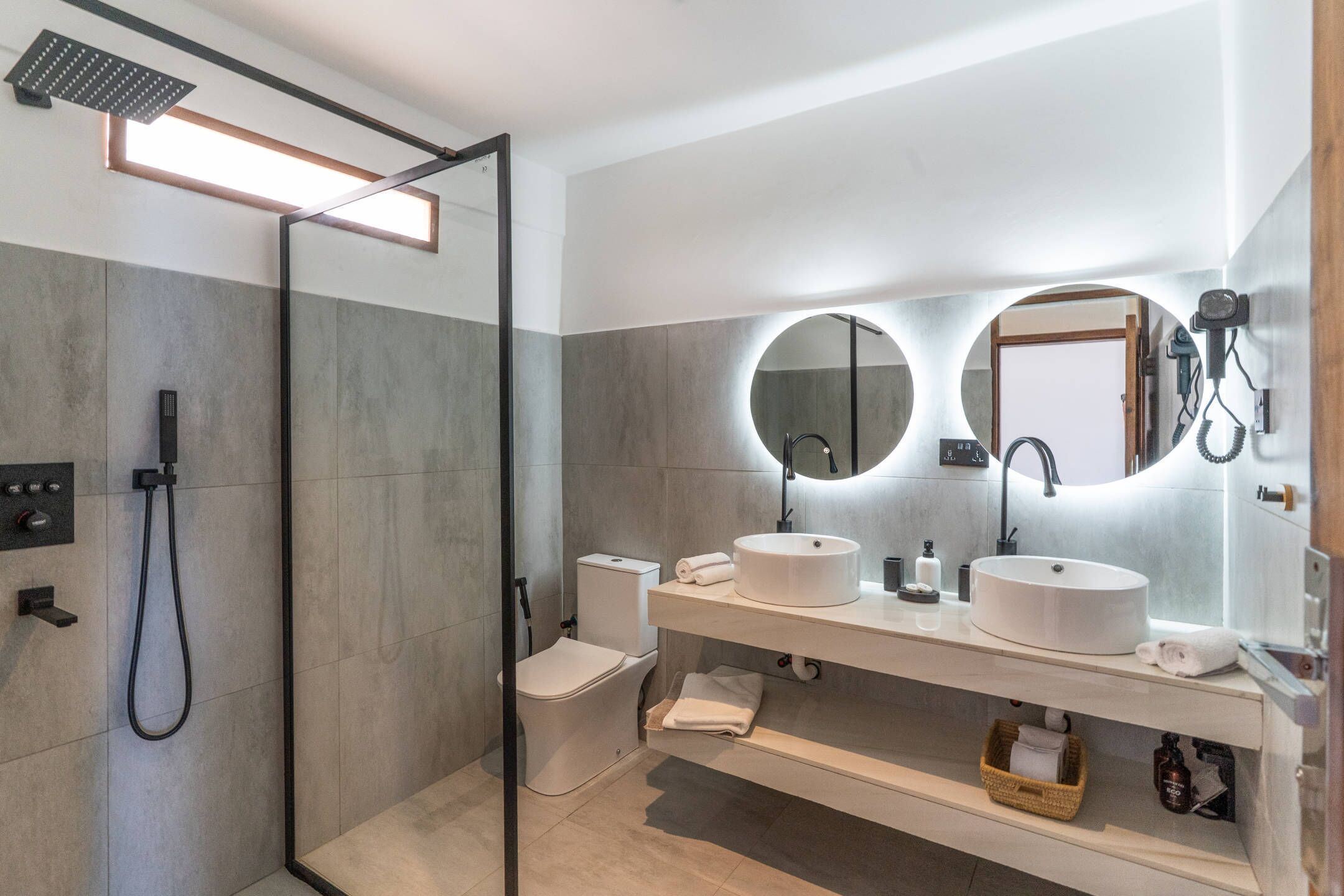 Un baño moderno con ducha acristalada, lavabo blanco y un espejo grande.