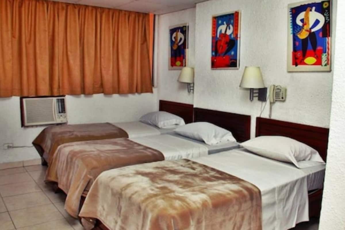 Une chambre d’hôtel avec deux lits, une fenêtre avec des rideaux, des lampes fixées au mur et un téléphone.