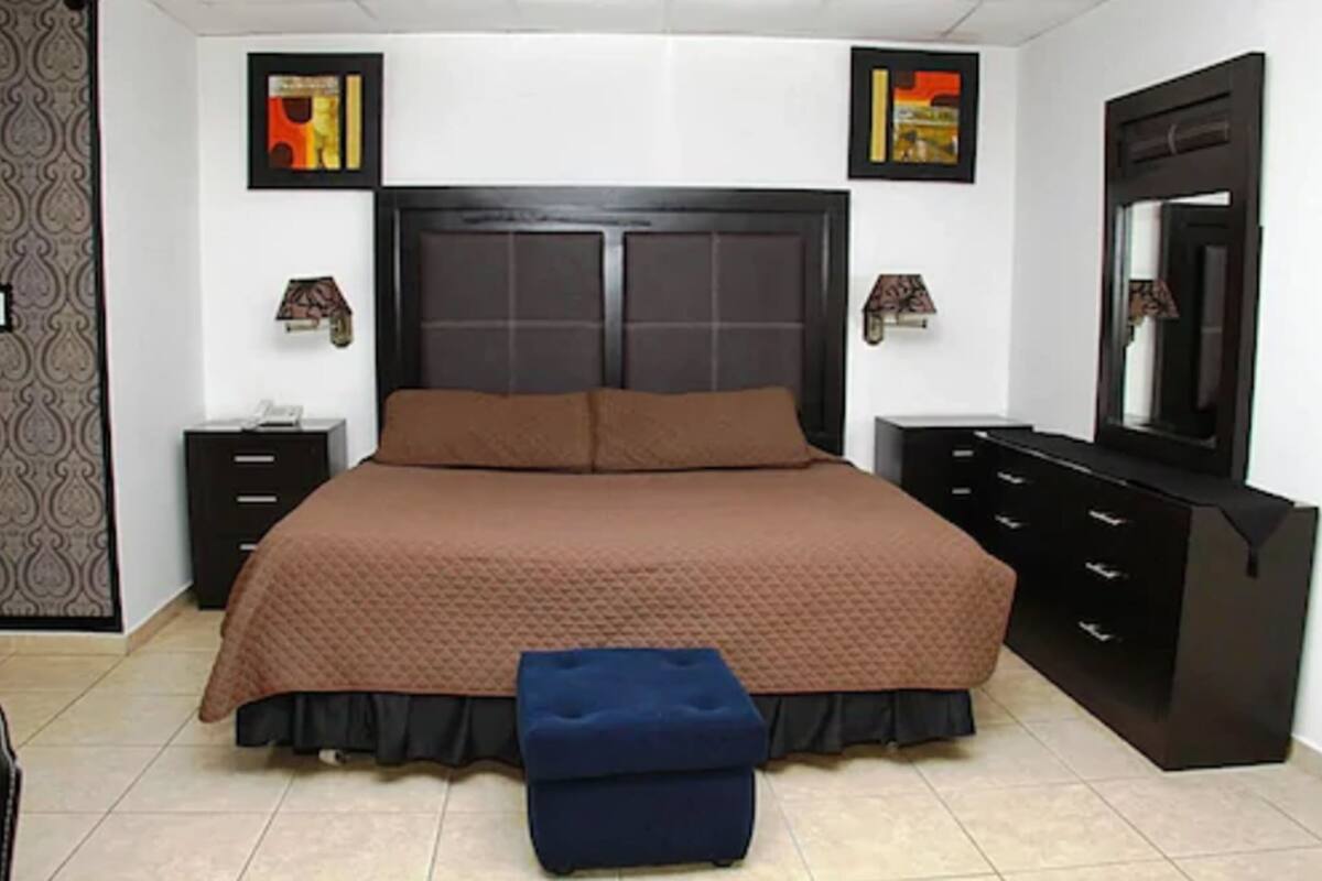 Une chambre à coucher avec un grand lit, une commode, une table de chevet et un miroir.