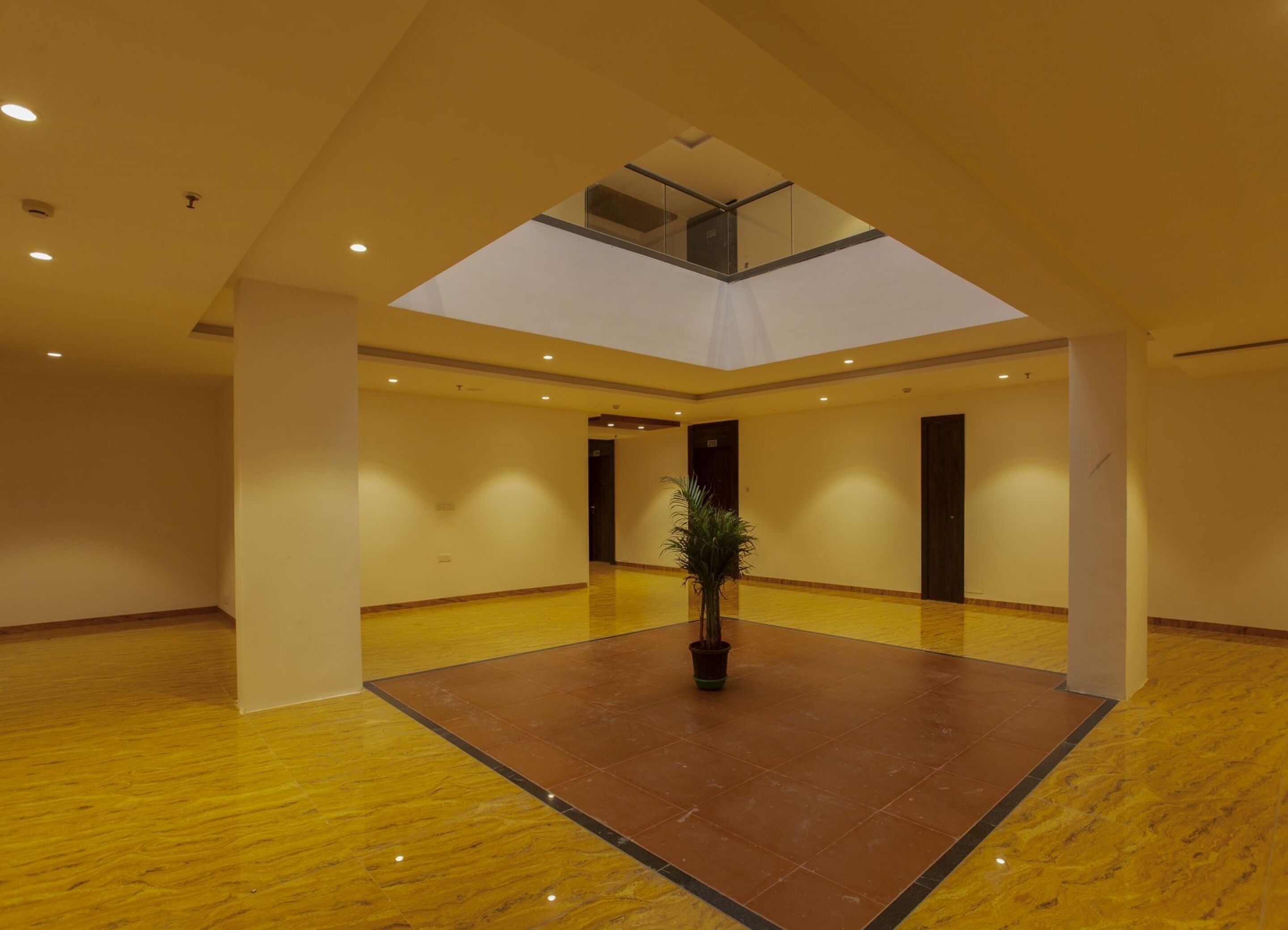A spacious atrium with a high ceiling, a skylight, and a central potted plant.