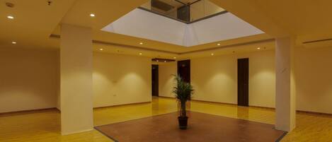 A spacious atrium with a high ceiling, a skylight, and a central potted plant.