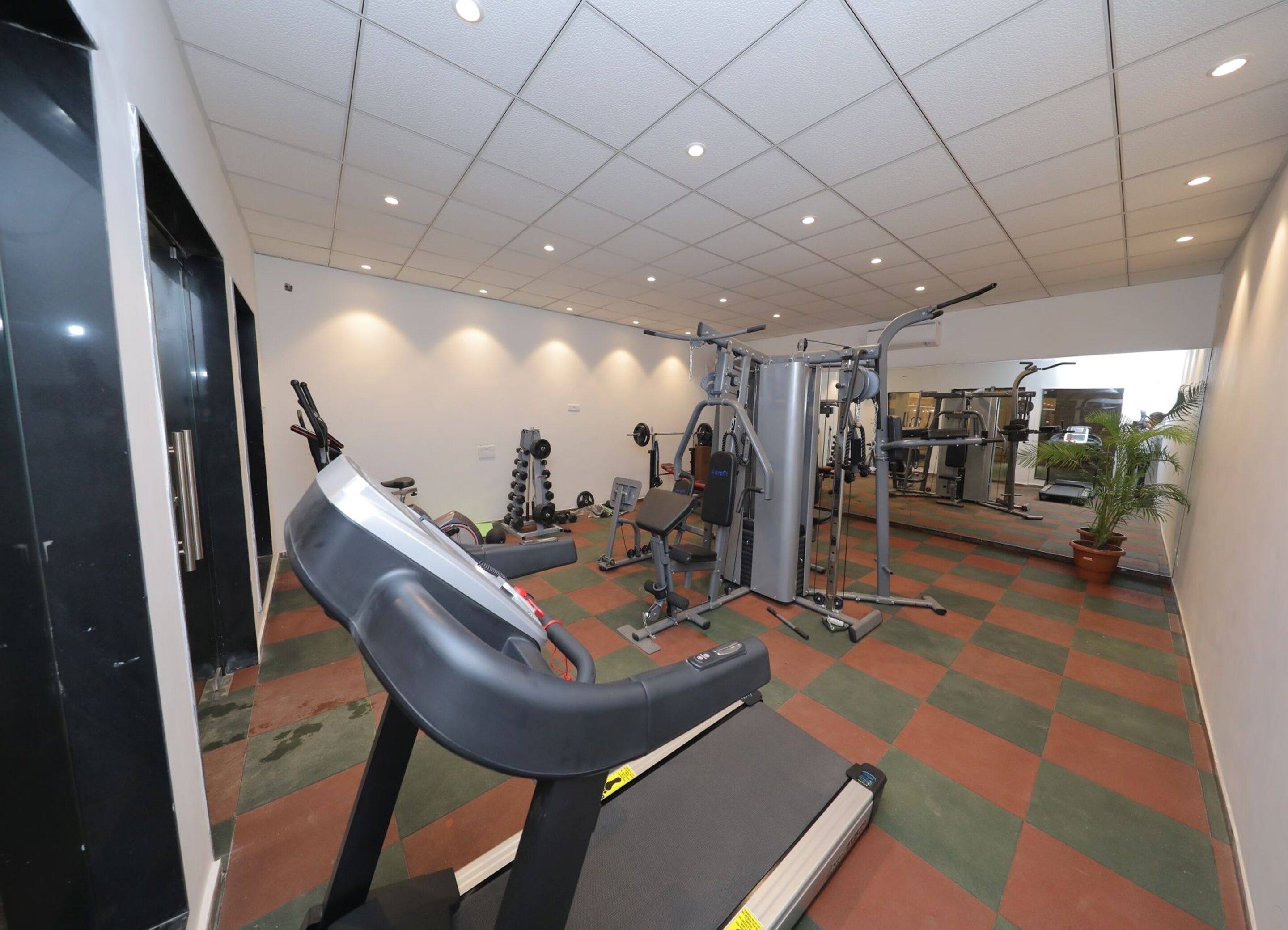 A gym with treadmills, weight machines, and a mirrored wall.
