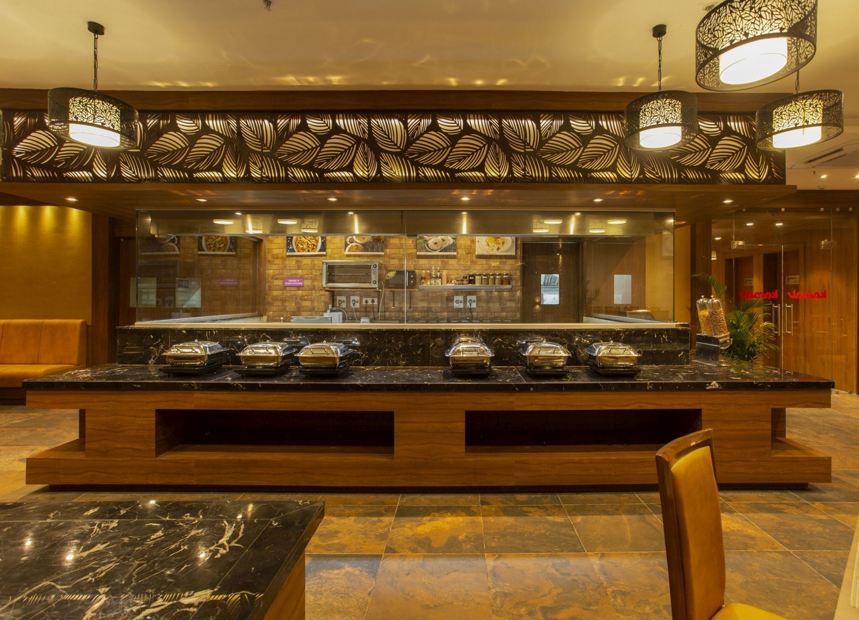 A hotel lobby with a marble reception desk, a seating area, and a buffet counter with covered food items.