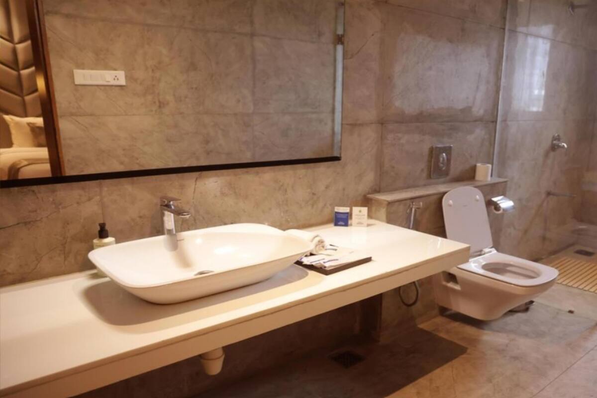 A bathroom with a large mirror, a sink, a toilet, and a shower area.