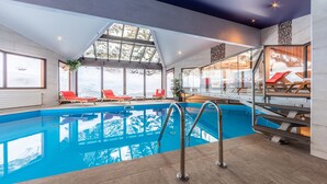 An indoor swimming pool with clear views of snowy mountains through large windows. - Hôtel Les Sherpas (Courchevel)