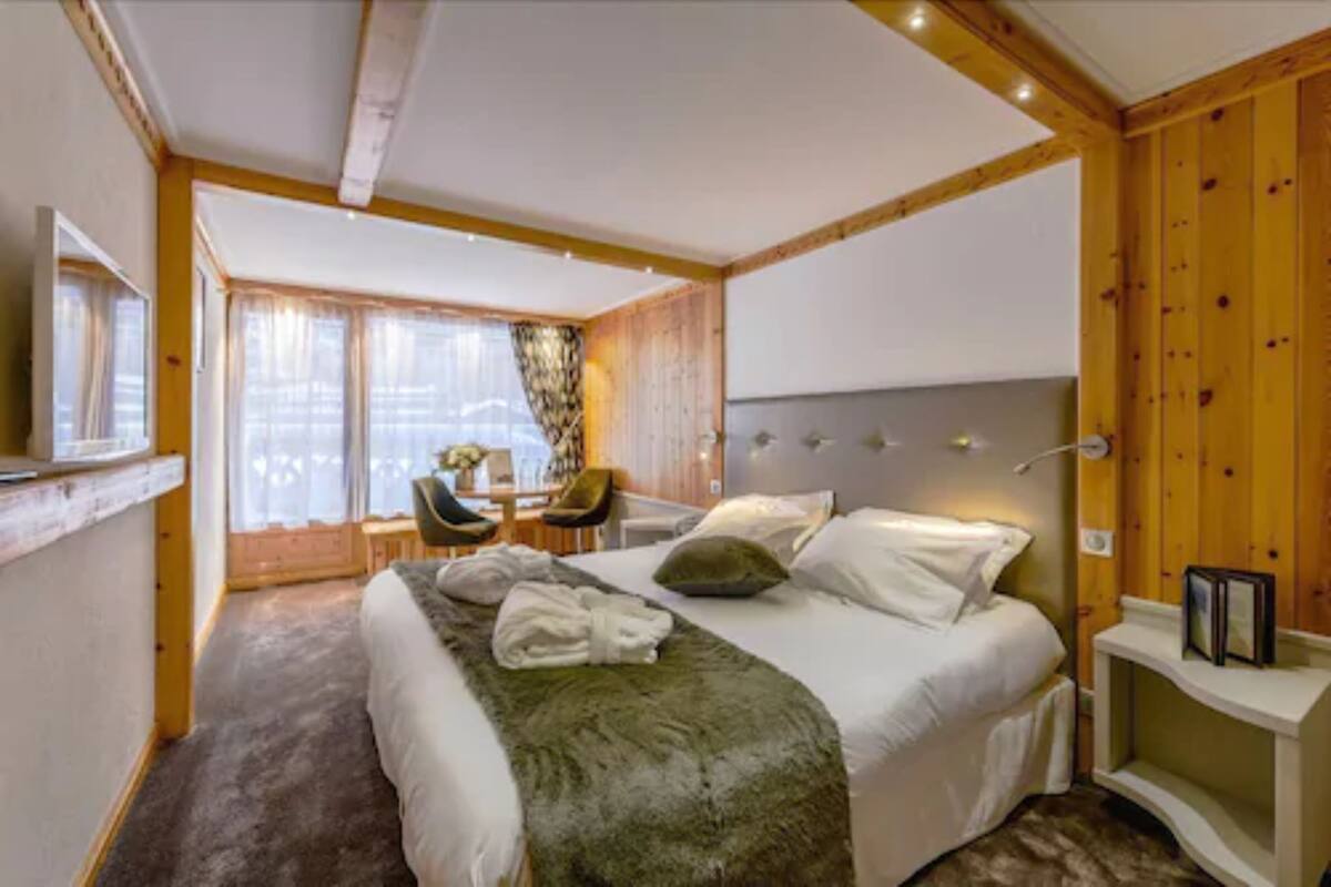 A bedroom with a bed, a desk, and a chair.