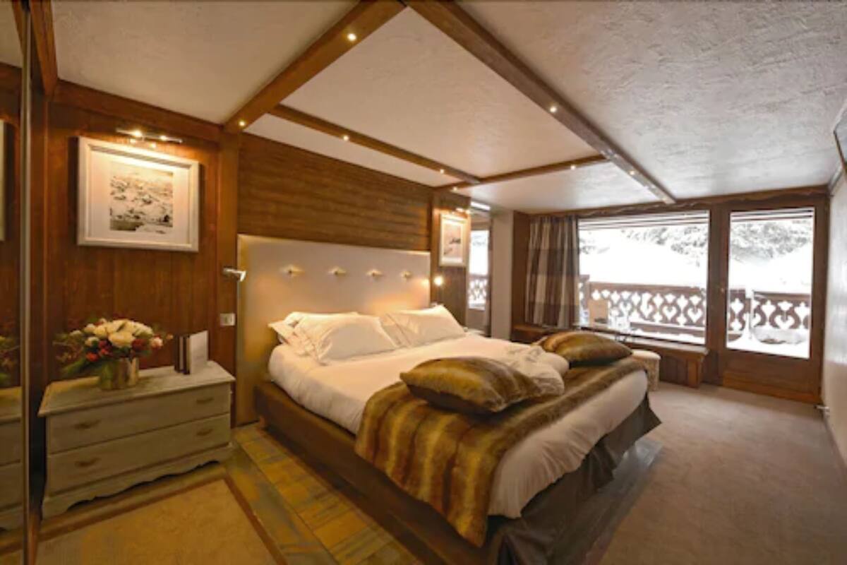 A bedroom with a large bed, wooden headboard, bedside tables, and a view through a window.