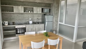 Una cocina moderna con una mesa y sillas de madera, electrodomésticos integrados y un salpicadero gris.
