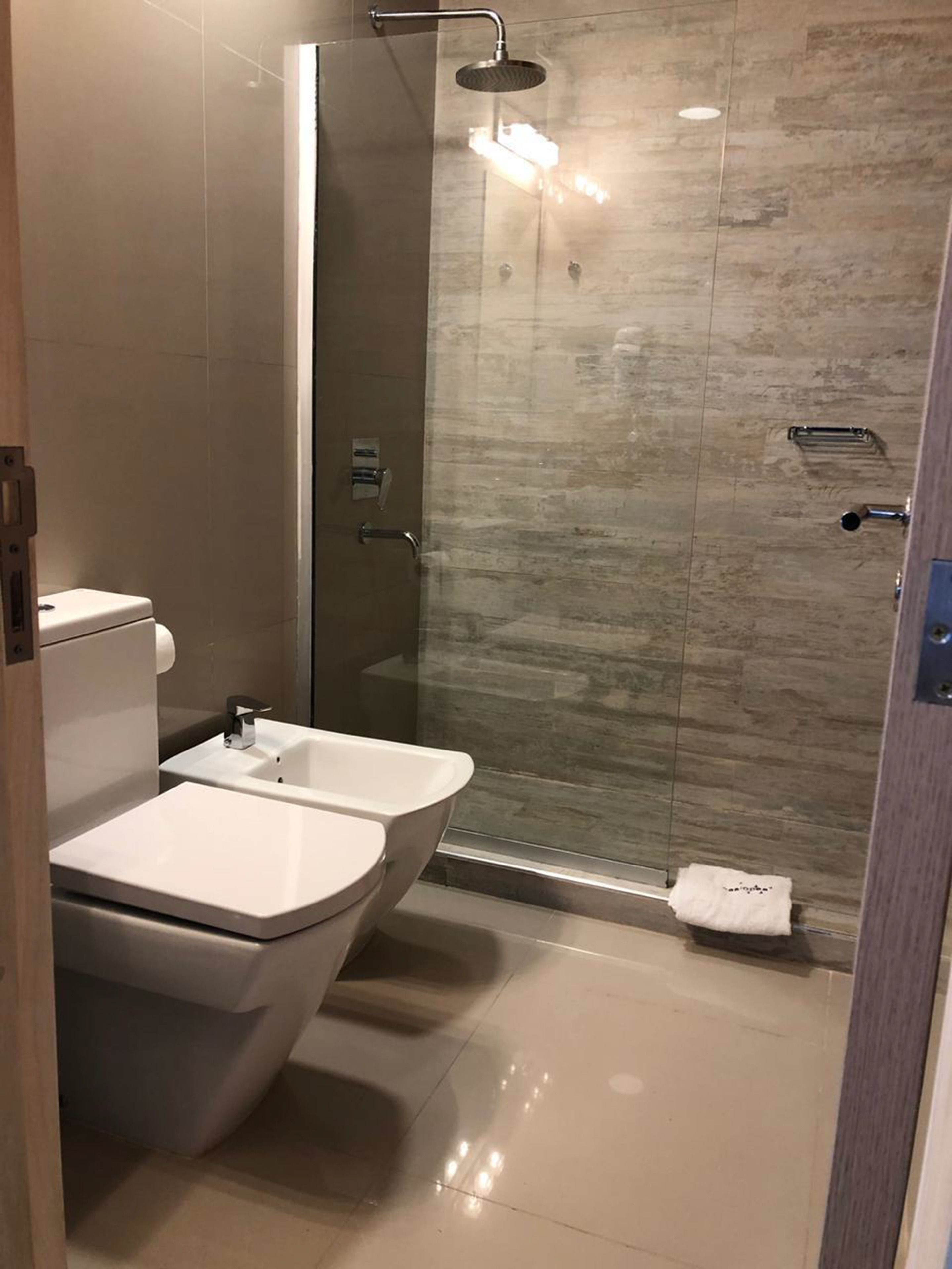 Ein modernes Badezimmer mit Duschkabine aus Glas, zwei Waschbecken und einer Toilette.