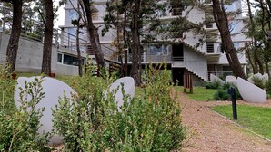 Un edificio moderno con diseño de varios niveles, rodeado de árboles y un camino de grava.