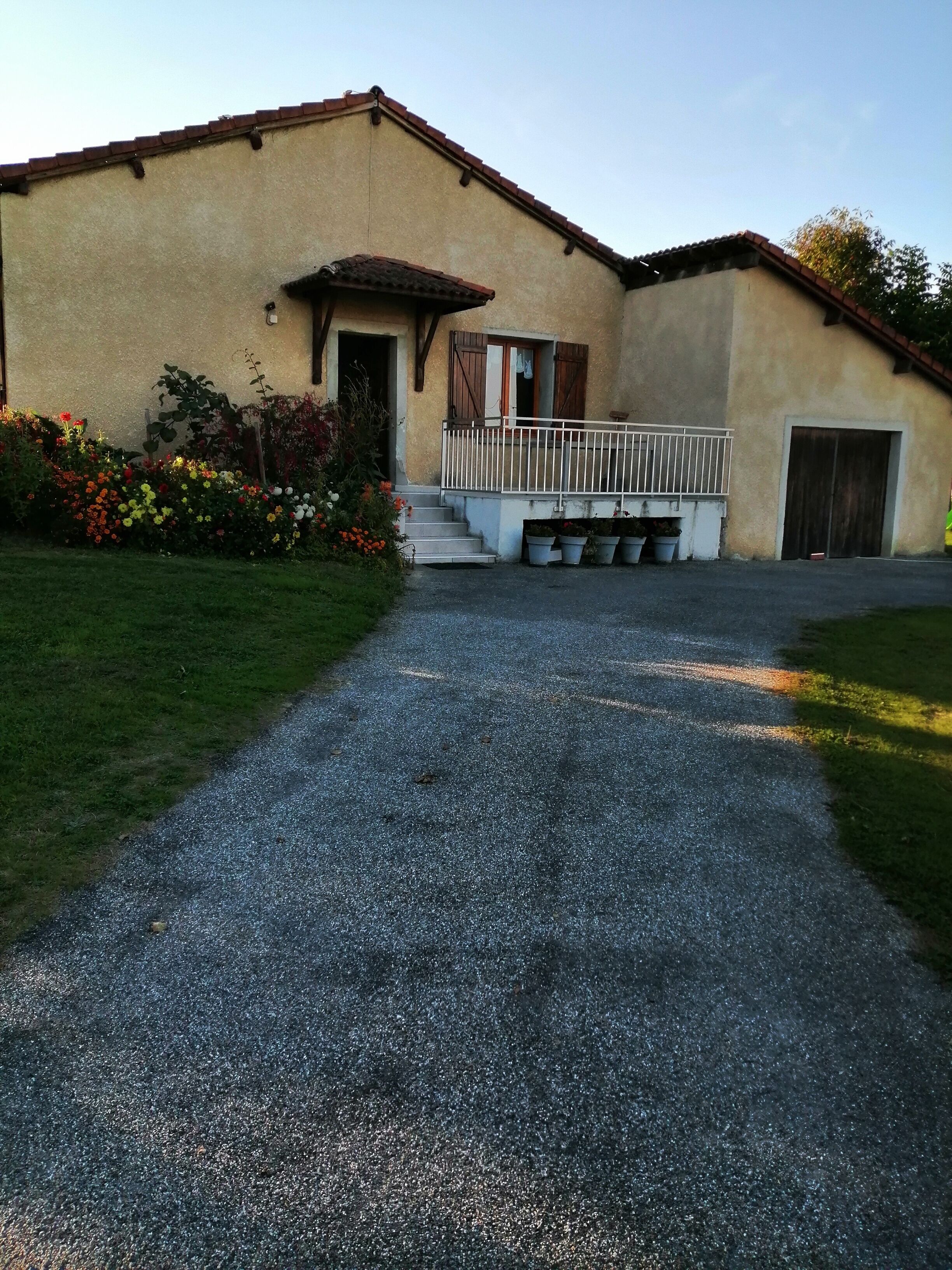 A building with a gravel driveway leading to a gated entrance.