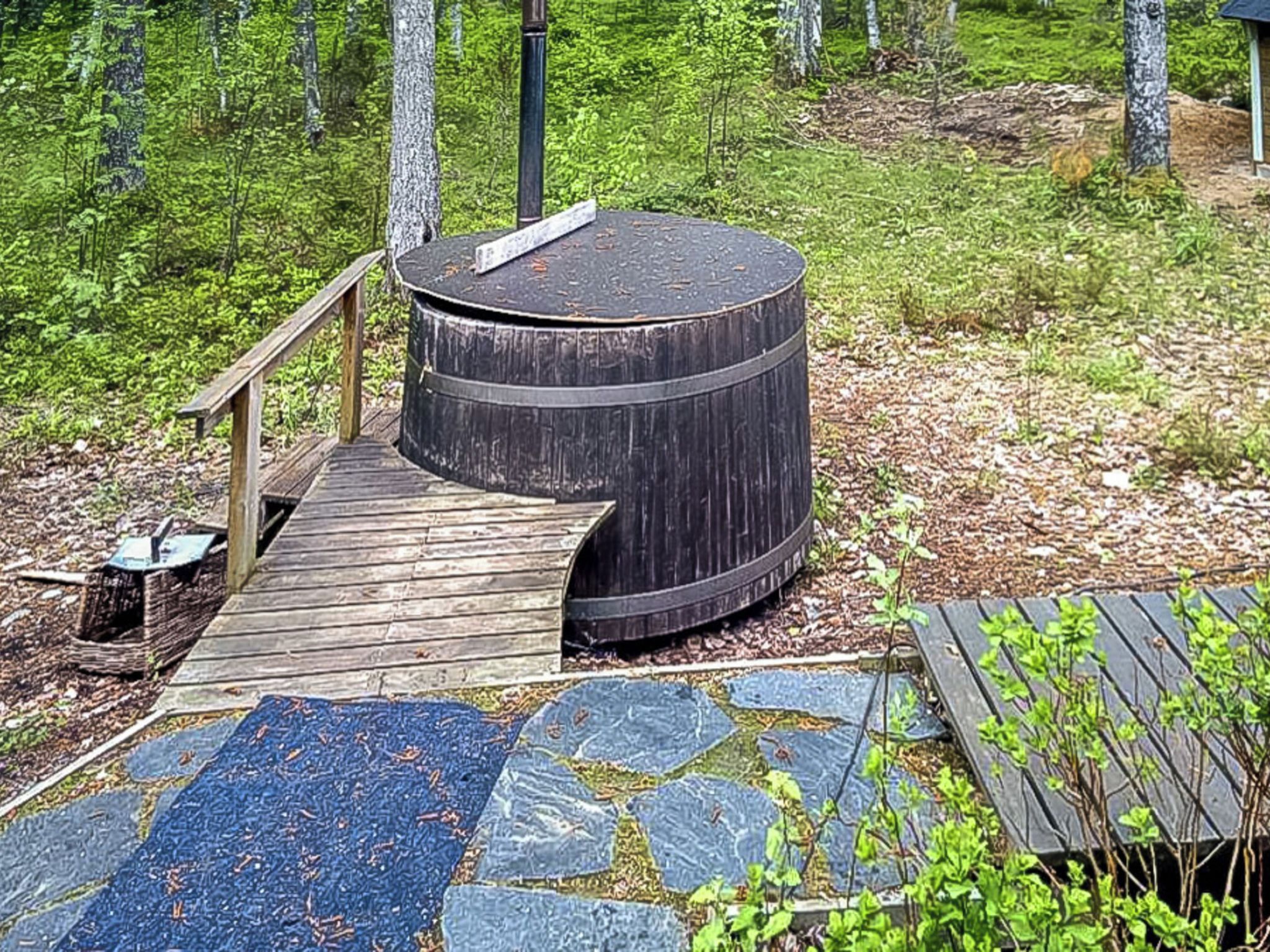 En rund trækonstruktion med en træterrasse, omgivet af skov.