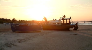 Two boats on a sandy beach with a sunset in the background. - Holiday and conference house Mutabor, in the resort, quiet, close to the beach, shops, pub (Seebad Ahlbeck)